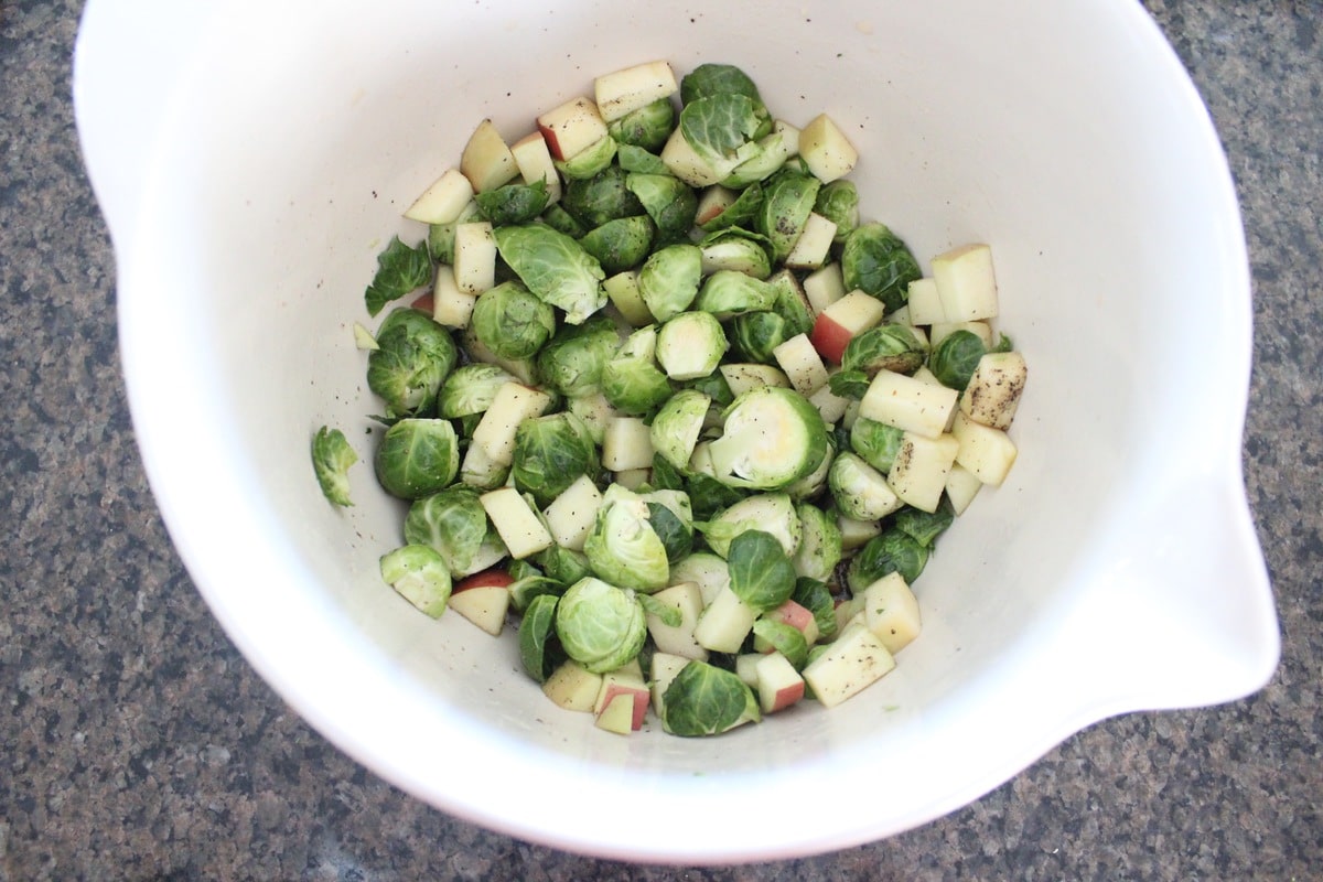 brussels sprouts and diced apples seasoned in large mixing bowl