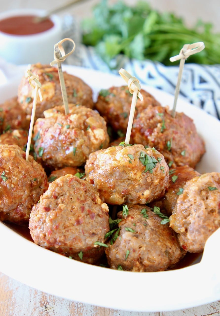 Taco meatballs in bowl with small wooden skewers with fresh cilantro