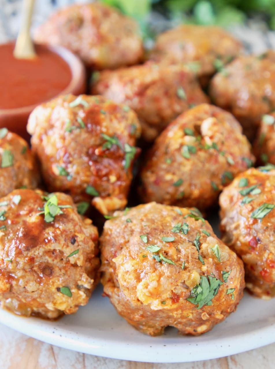 Taco meatballs on plate with small bowl of hot sauce