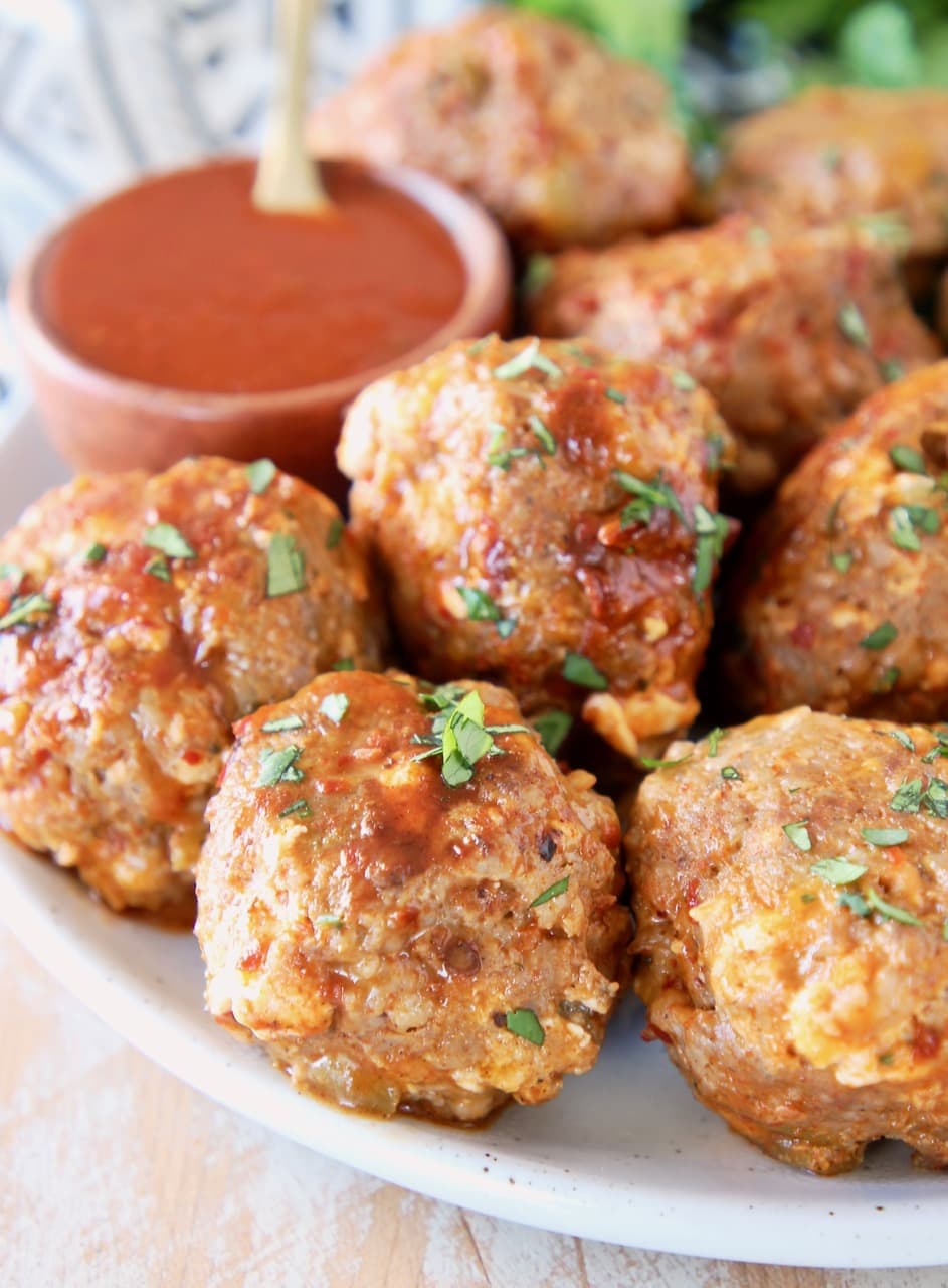 Taco meatballs on plate with small wooden bowl filled with hot sauce