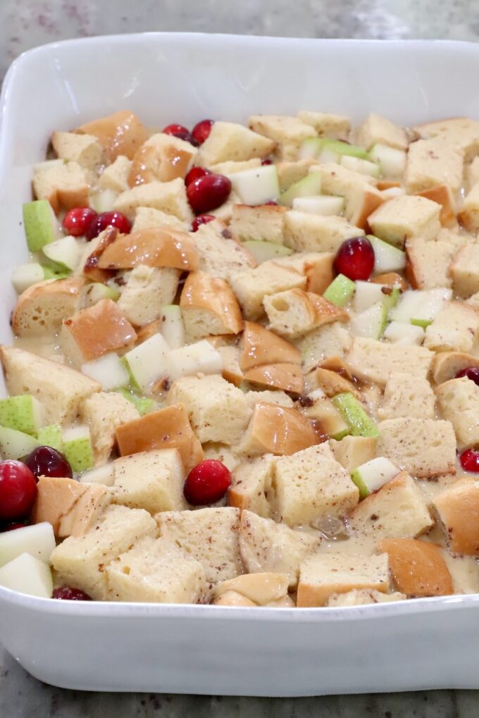 soaked bread cubes in a casserole dish with diced pears and cranberries