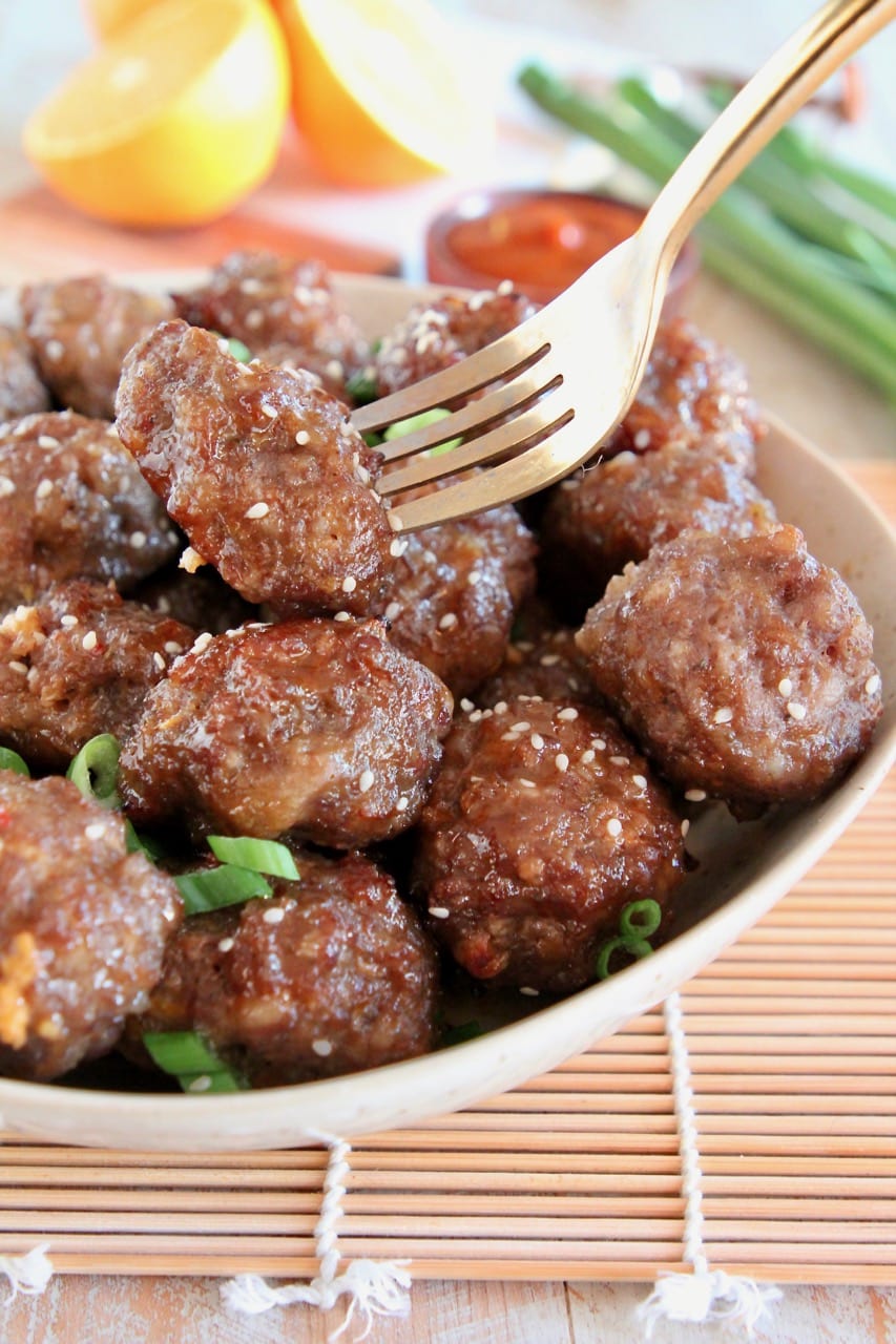 Chinese Meatballs in bowl, with gold fork holding up one meatball