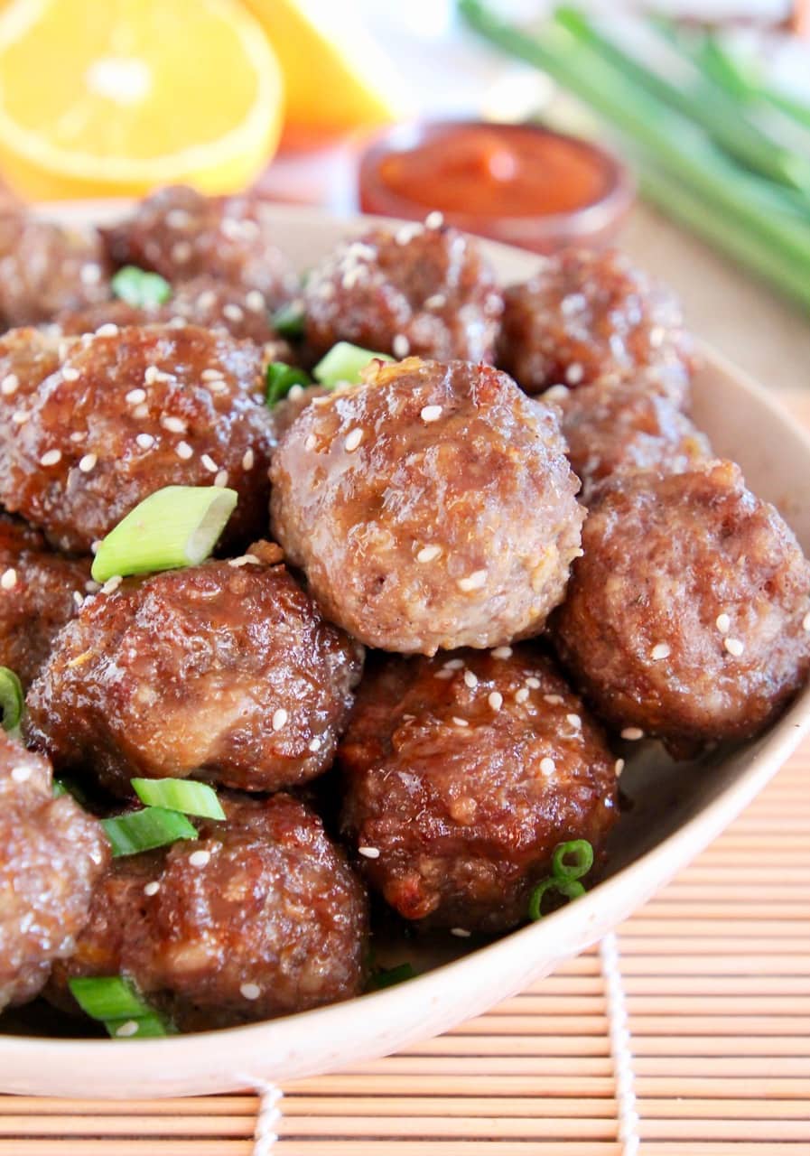 Chinese meatballs in bowl, topped with sesame seeds and green onions