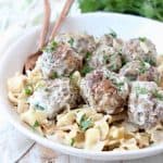Swedish meatballs in bowl with cooked egg noodles and copper forks