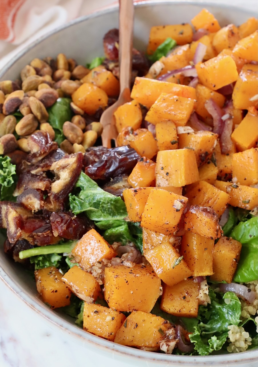 roasted butternut squash  on top of a salad in a bowl