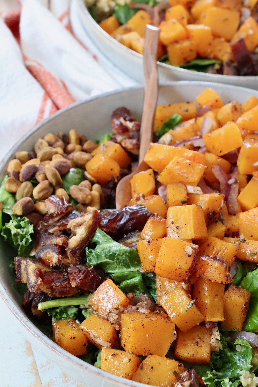 roasted diced butternut squash on top of a salad in a bowl