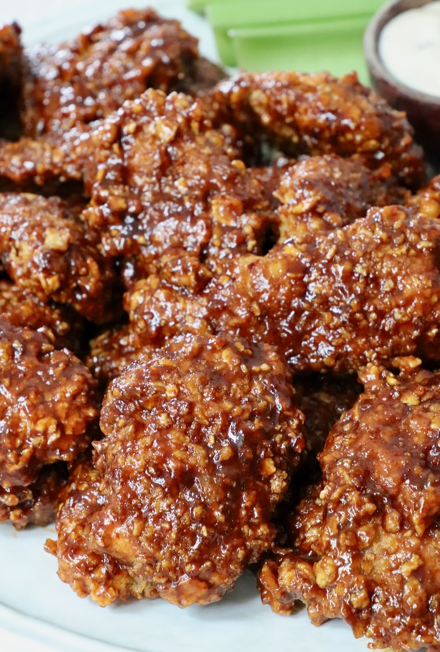 cooked chicken crispers tossed in chipotle honey sauce stacked up on a plate