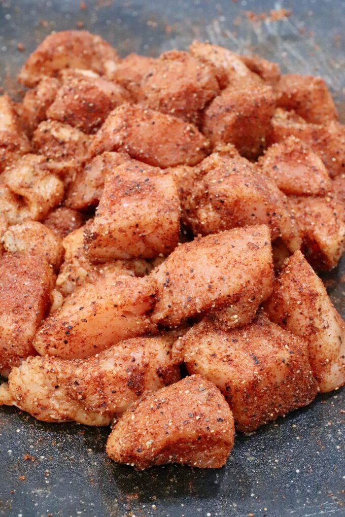 seasoned raw cubes of chicken on a cutting board