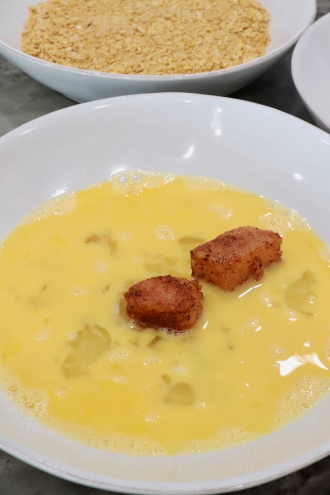 seasoned raw pieces of chicken in a bowl of whisked eggs