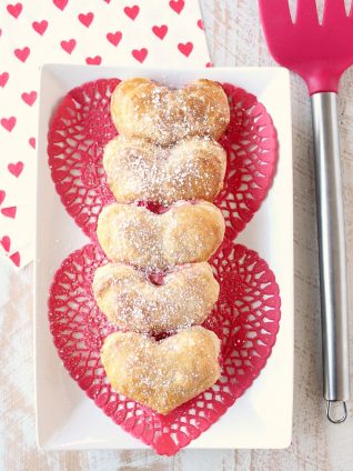 Strawberry cheesecake filling is wrapped up in heart shaped puff pastry dough in this mini strawberry cheesecake pie recipe, perfect for Valentine's Day!