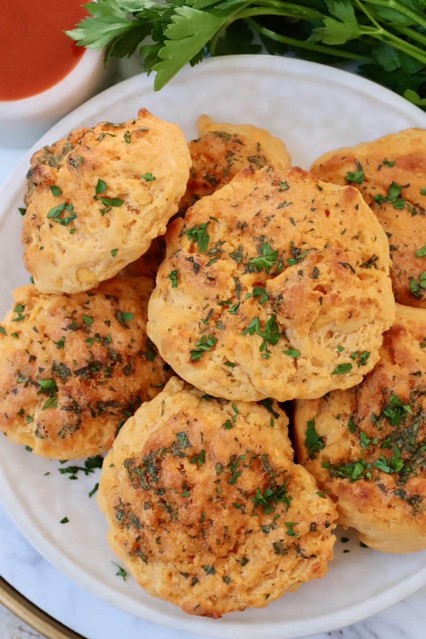 cheddar biscuits stacked up on a plate with fresh parsley