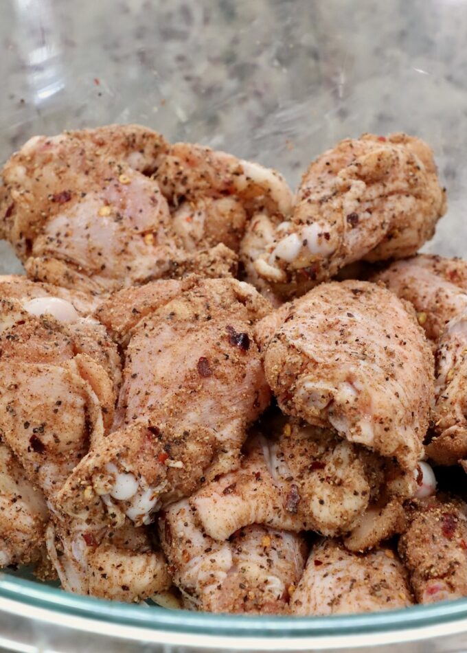 seasoned raw chicken wings in a glass bowl