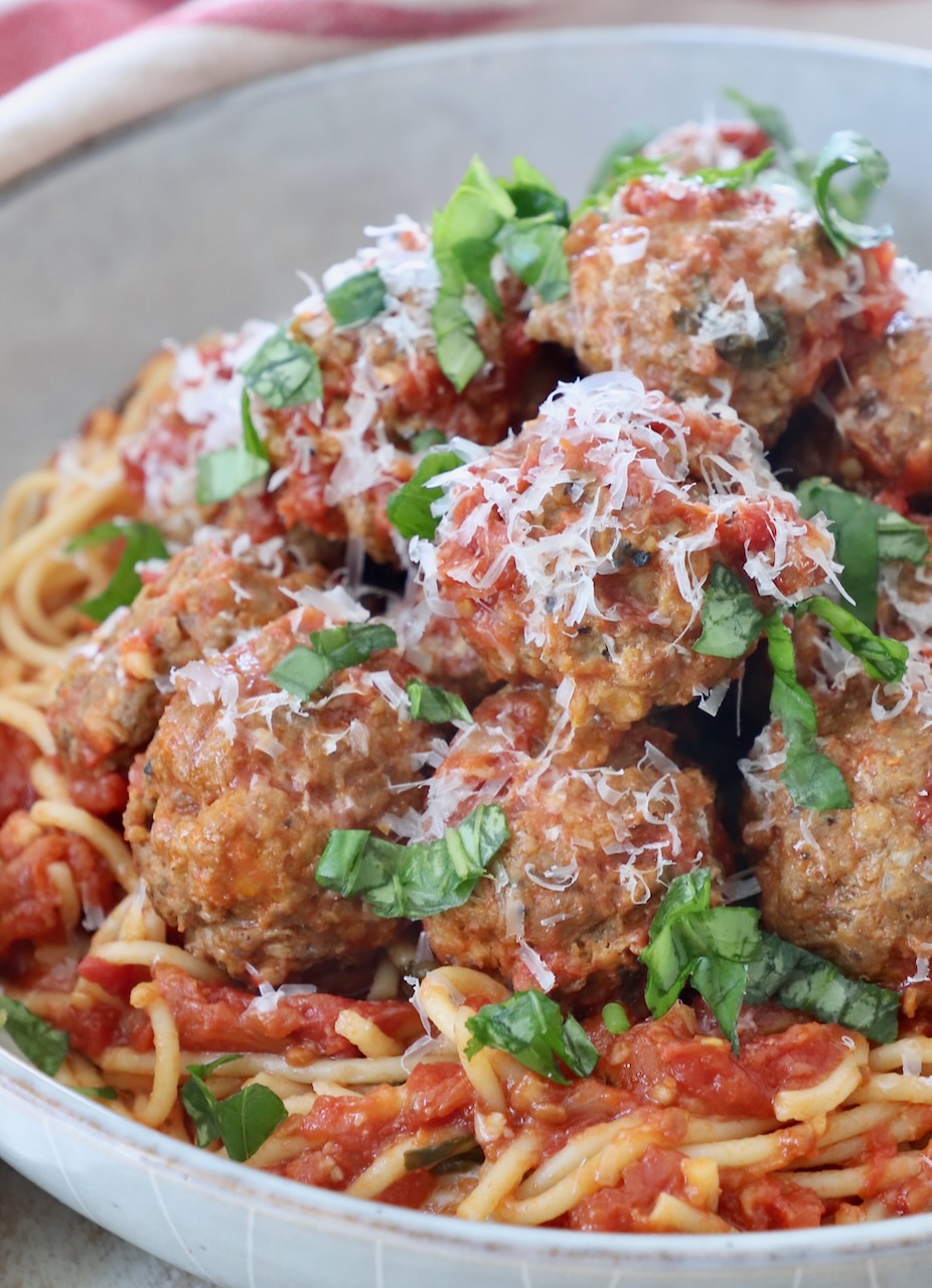 cooked meatballs in bowl with tomato sauce and cooked spaghetti noodles
