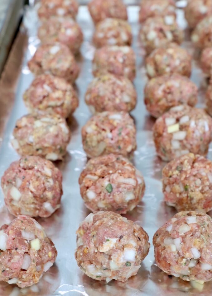 uncooked meatballs on foil lined baking sheet