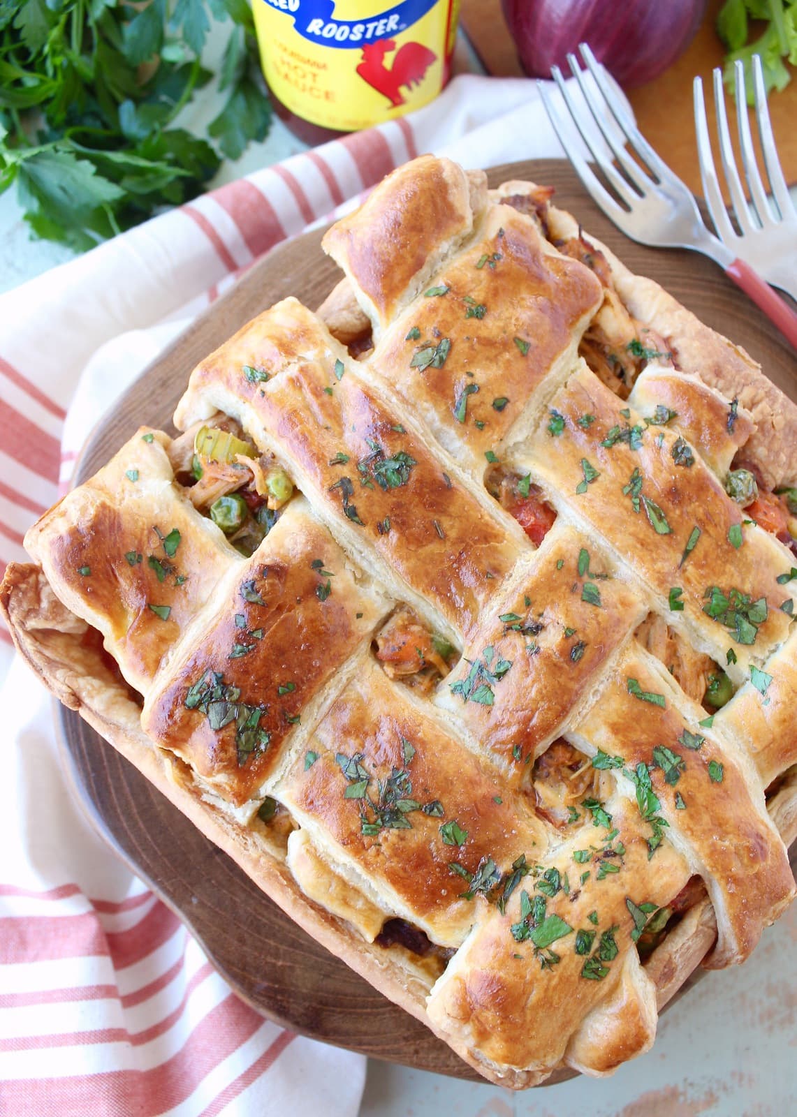 baked chicken pot pie with a braided puff pastry crust on a wood board