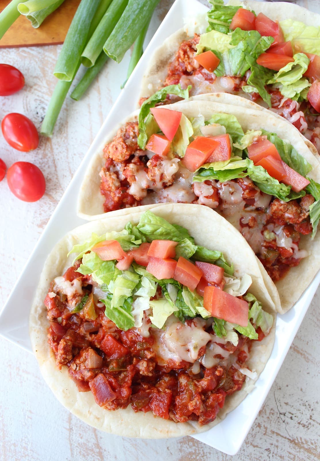 Three tacos filled with ground turkey, salsa, cheese, lettuce, and tomato.