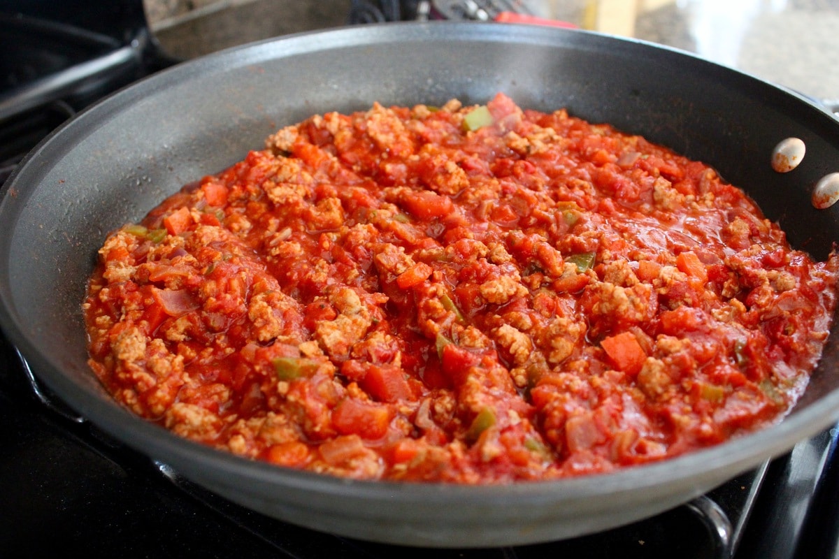 Ground turkey in a red sauce cooking in a skillet.