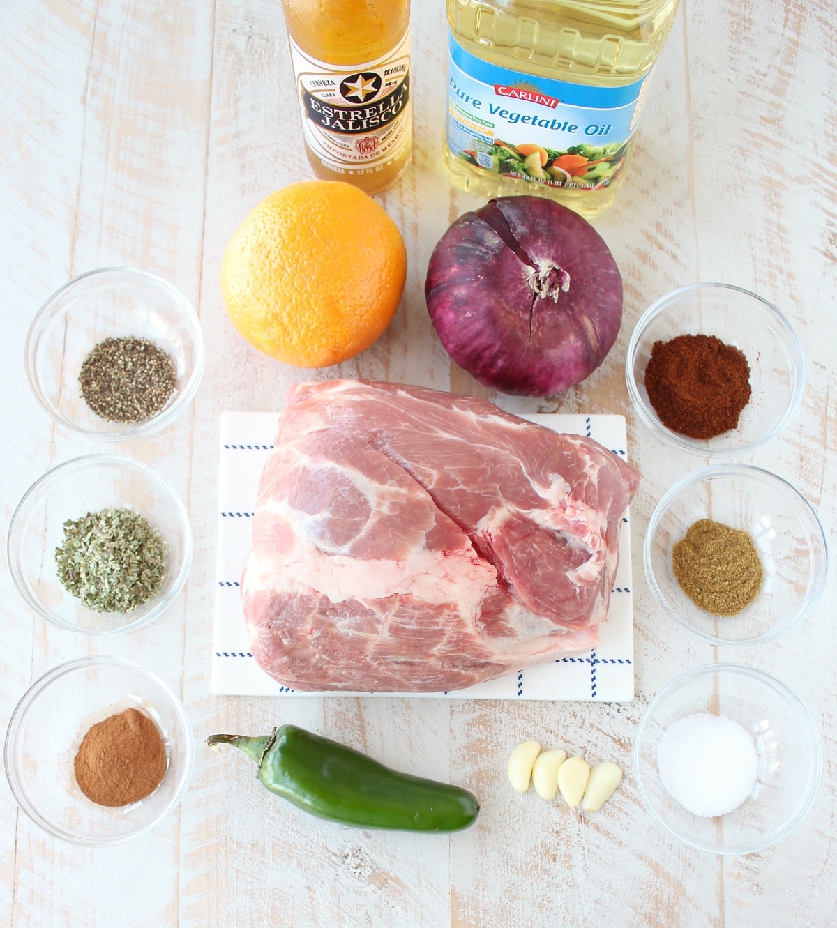 Ingredients for slow cooker carnitas on white wood board