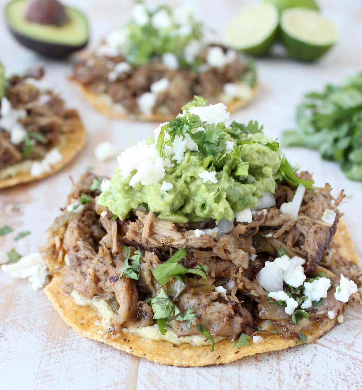 shredded carnitas pork on tostada shell, topped with guacamole and cotija cheese