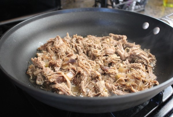 shredded pork cooking in oil in large skillet on the stove