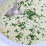queso blanco in slow cooker topped with fresh cilantro with serving spoon
