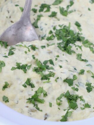 queso blanco in slow cooker topped with fresh cilantro with serving spoon