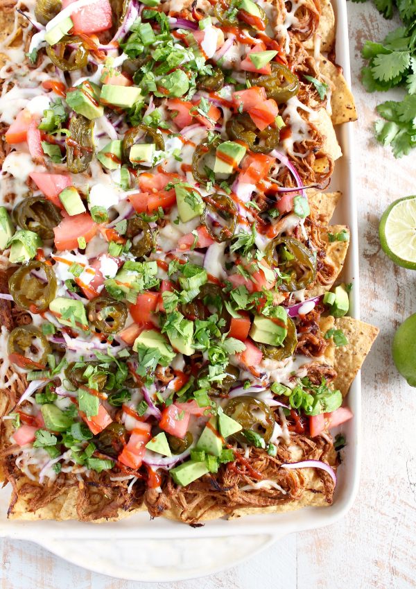 Pulled Pork Nachos on a baking sheet on a wooden surface. 