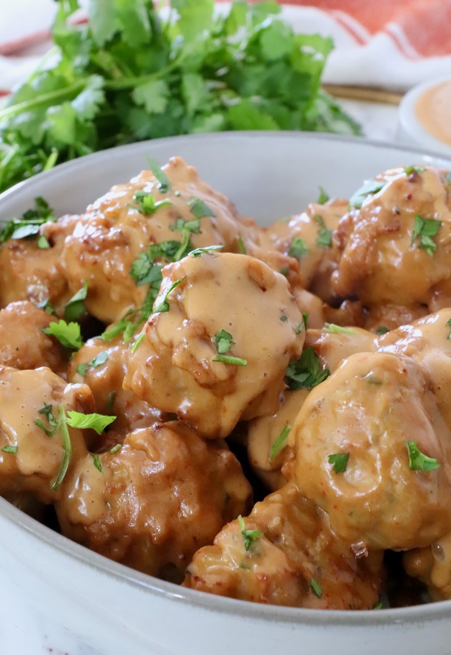 meatballs covered in Thai peanut sauce in a bowl