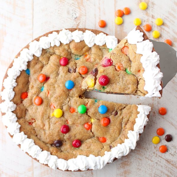 The Ultimate Candy Cookie Cake recipe is perfect for Halloween, birthdays or holidays, add your favorite candy to cookie dough & bake into a tasty cake!