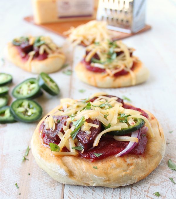 Sriracha pizza sauce, jalapenos, summer sausage and jalapeno cheddar cheese top this delicious mini pizza recipe, perfect for game days and parties!
