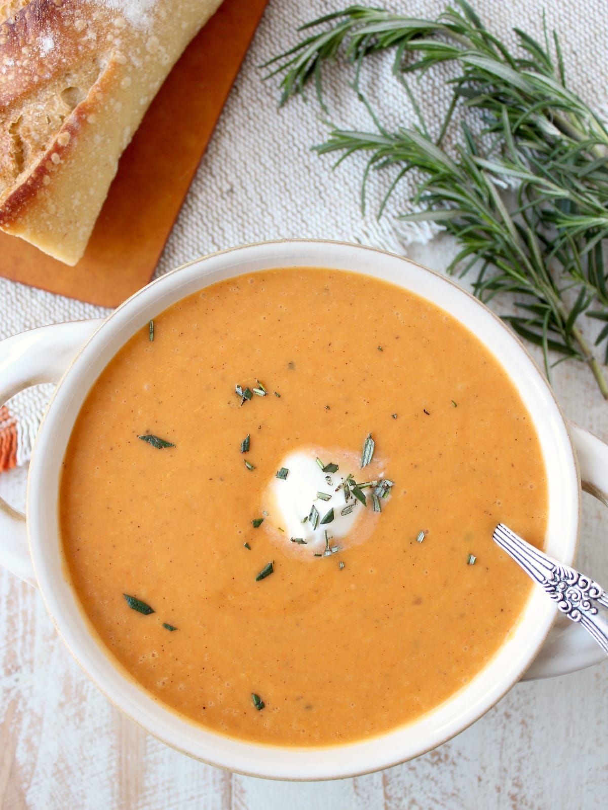 sweet potato soup in bowl with spoon, topped with sour cream