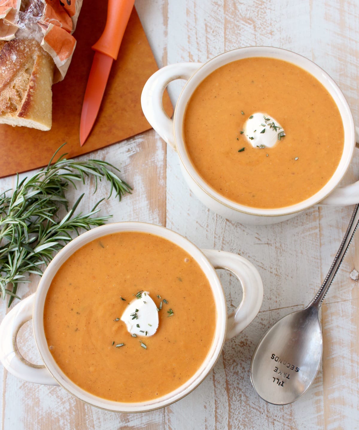 sweet potato soup in two bowls with spoon on the side