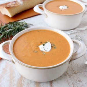 sweet potato soup in two bowls topped with sour cream