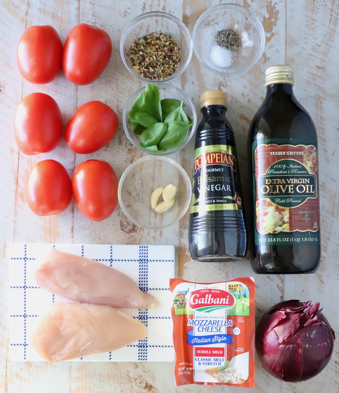 ingredients for bruschetta chicken on a white wood board