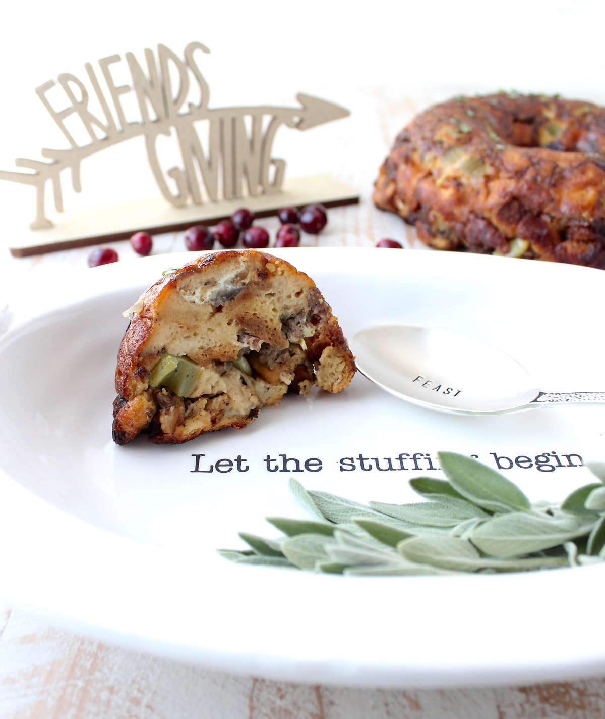 A slice of bundt pan stuffing on a white plate with a spoon and herbs. 
