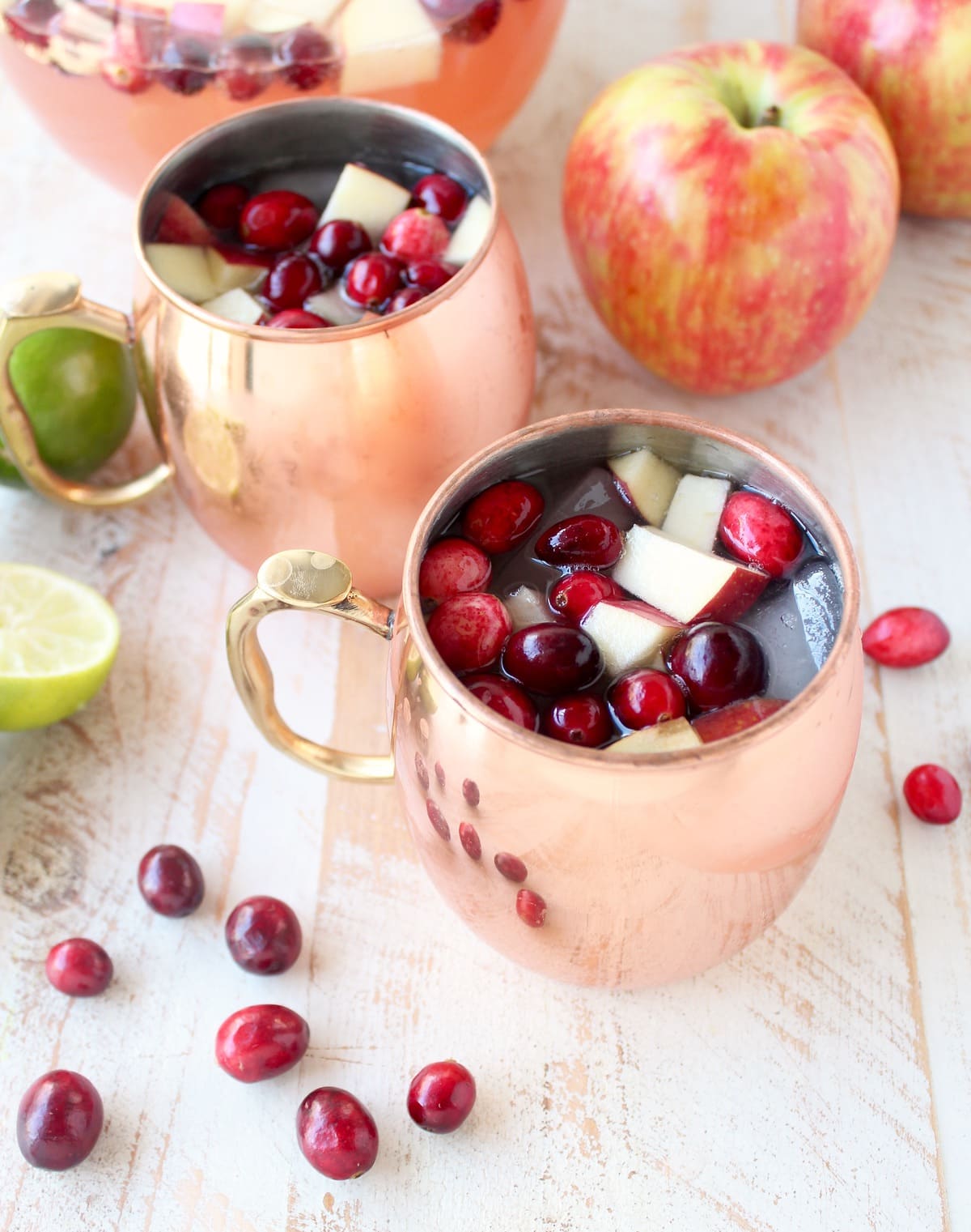 moscow mule punch in copper mugs topped with diced apples and fresh cranberries
