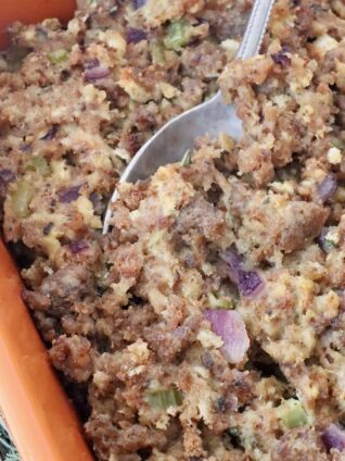 sausage stuffing in a casserole dish with a serving spoon