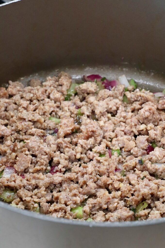 cooked, crumbled pork sausage in a large pan with diced vegetables