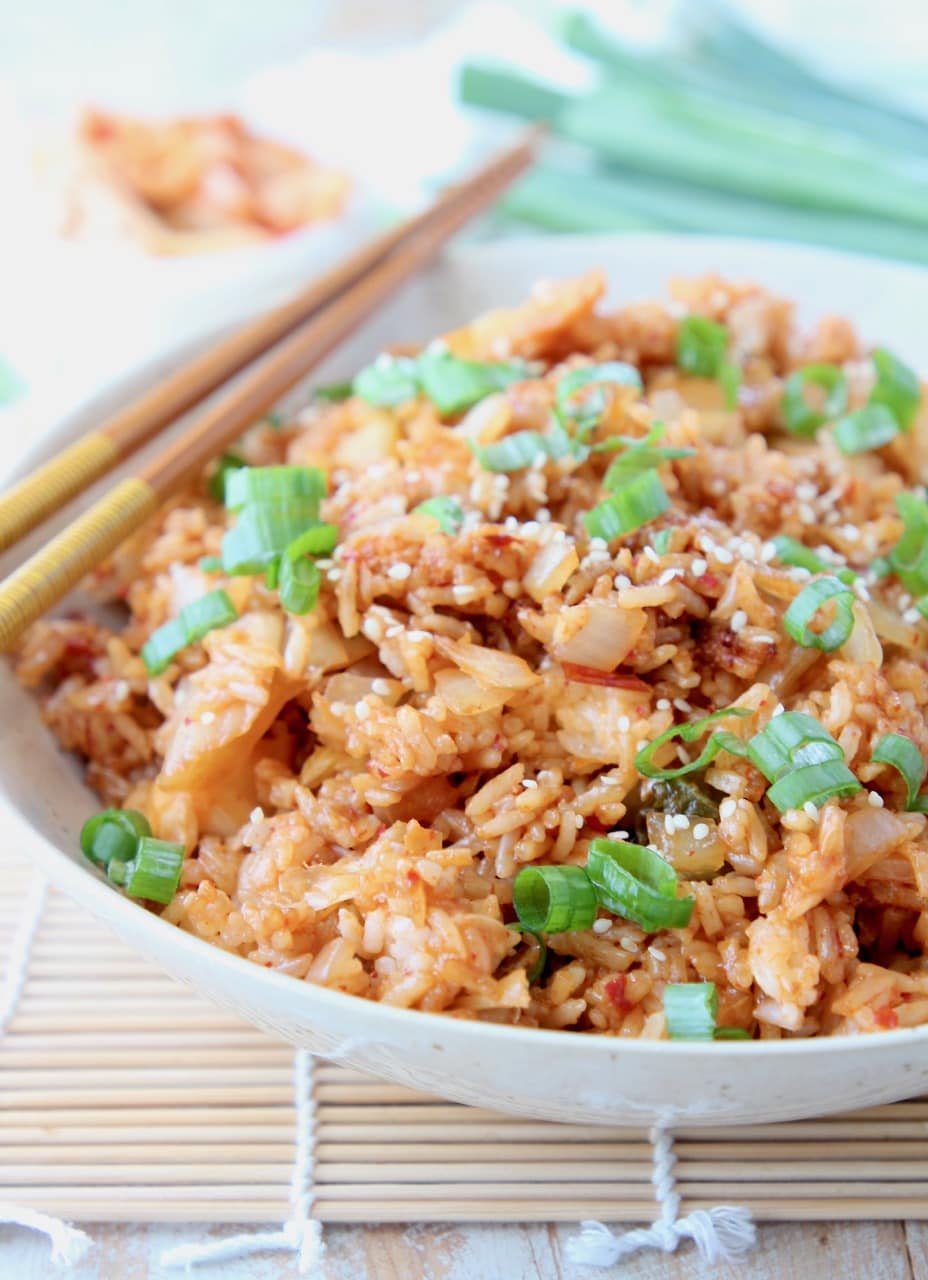Fried rice in bowl with chopsticks, topped with diced green onions