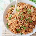 Kimchi fried rice in bowl with spoon and topped with diced green onions
