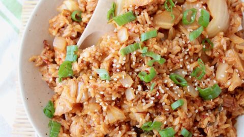 Kimchi fried rice in bowl with spoon and topped with diced green onions