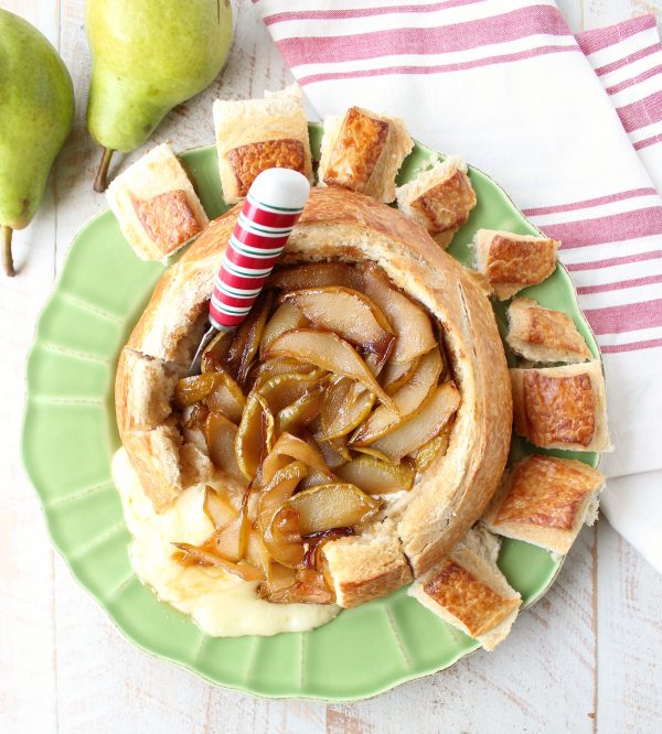 Bread bowl with baked brie, caramelized pears and red, white and green cheese spreader