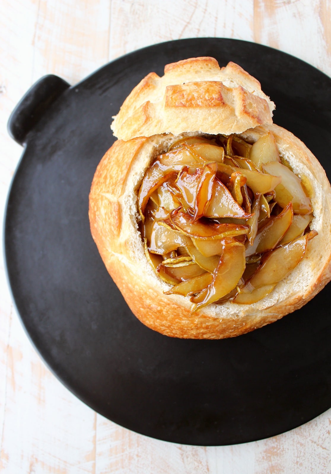 bread bowl on baking sheet filled with brie and caramelized pears