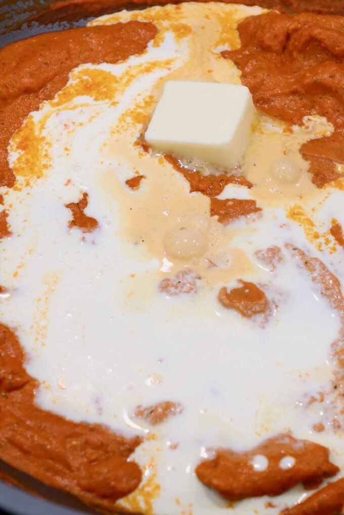 melted butter on top of butter chicken curry in large pan