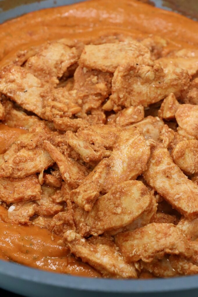cooked sliced chicken in butter curry sauce in large skillet