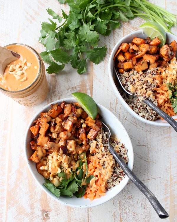 Overhead shot of Sweet Potato Buddha Bowls with a mason jar of Thai peanut sauce on the side