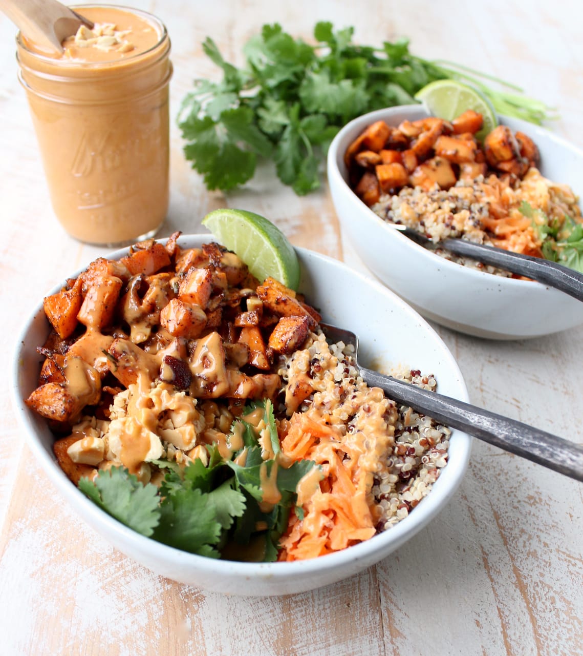 Roasted sweet potatoes in bowls with quinoa, shredded carrots and cilantro