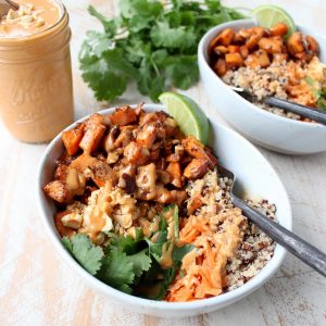 Roasted sweet potatoes and quinoa are topped with delicious Thai peanut sauce in this healthy, gluten free & vegan buddha bowl recipe!