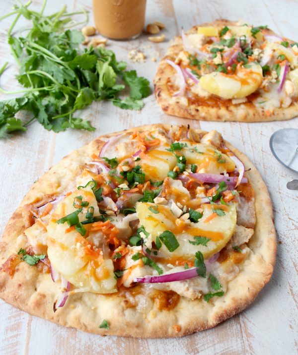 This easy naan pizza recipe is made in under 30 minutes with Thai peanut chicken, red onion, pineapple & mozzarella for a delicious combination of flavors!