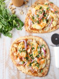 This easy naan pizza recipe is made in under 30 minutes with Thai peanut chicken, red onion, pineapple & mozzarella for a delicious combination of flavors!